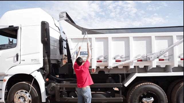 Caminhoneiro preparando o caminhão para realizar o transporte de cargas.